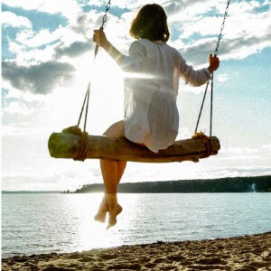 woman on a large wooden swing over looking the water